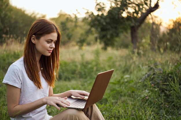 Mujer joven usando una tableta digital mientras está sentada en el campo