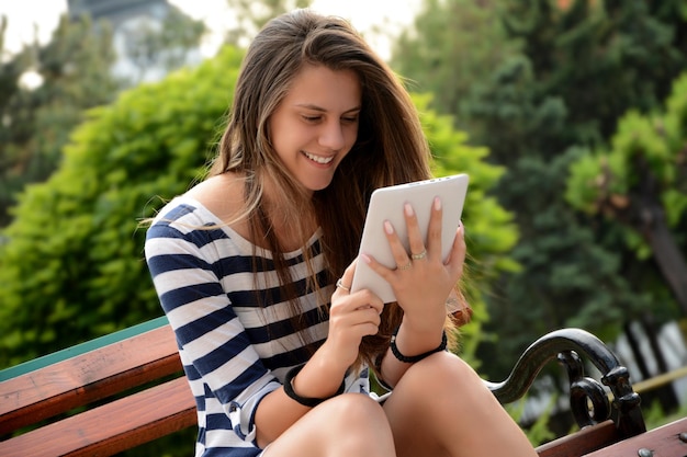 Mujer joven usando una tableta digital en el parque