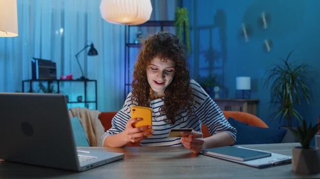 Mujer joven usando tarjeta de crédito bancaria y teléfono inteligente transfiriendo dinero compras compras en línea