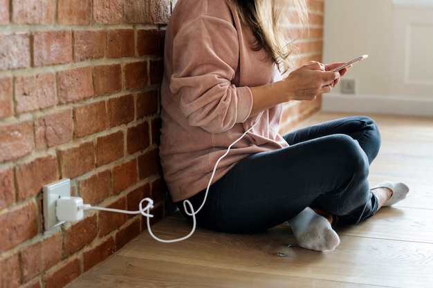 Mujer joven usando un teléfono inteligente, ya que se está cargando