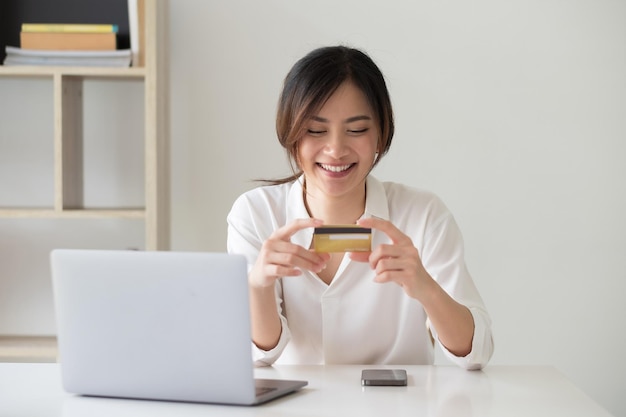 Mujer joven usando el teléfono mientras está sentada en la computadora portátil