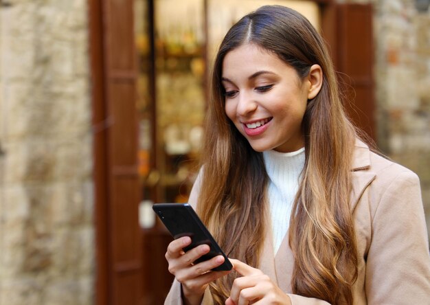 Foto mujer joven usando el teléfono mientras está de pie en la ciudad