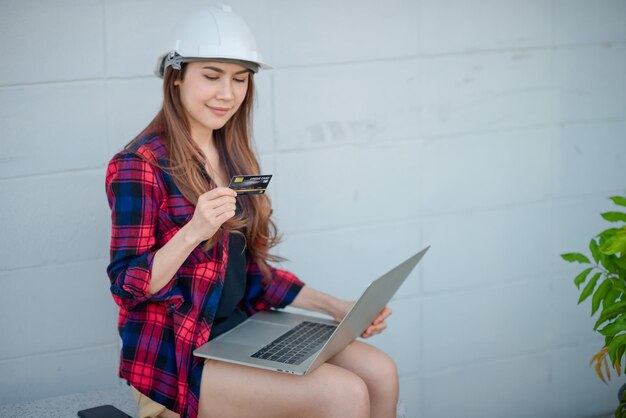 Foto mujer joven usando el teléfono mientras está sentada en la pared