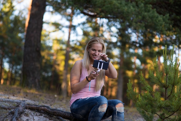 Mujer joven usando teléfono móvil en el bosque