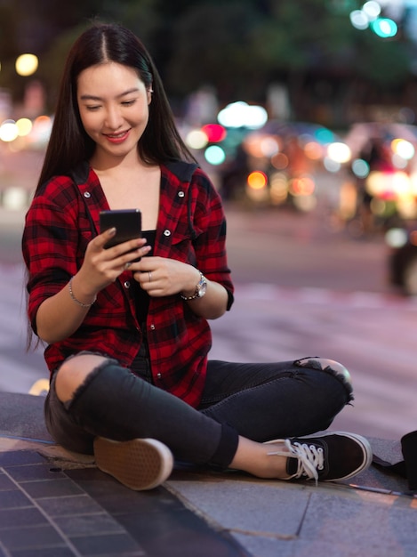 Mujer joven usando teléfono móvil en la ciudad