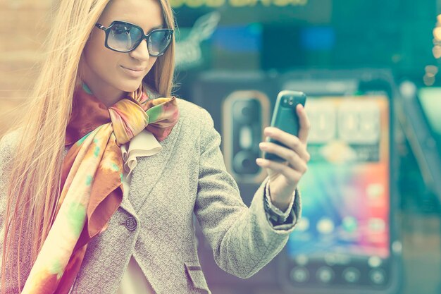 Mujer joven usando teléfono móvil en la ciudad