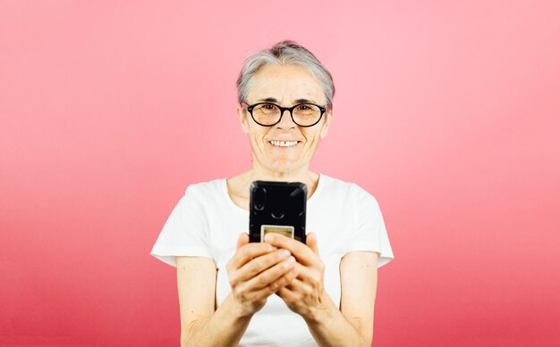 Foto mujer joven usando teléfono móvil contra un fondo rosa