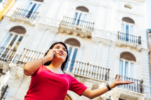 Foto mujer joven usando teléfono móvil en edificios de la ciudad