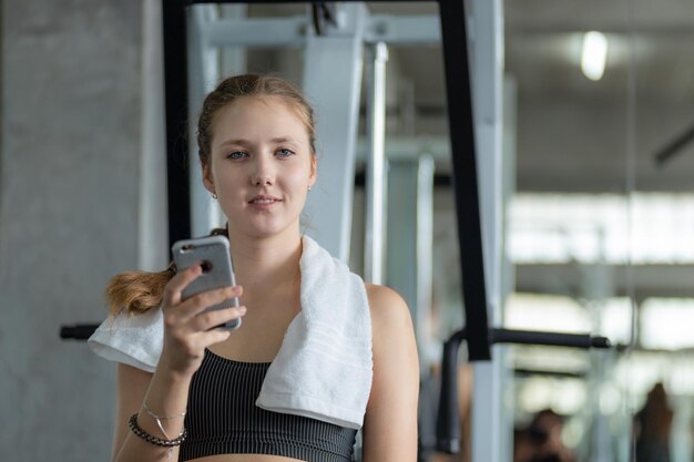 Mujer joven usando teléfono móvil en el gimnasio