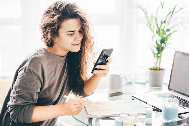Mujer joven usando teléfono móvil mientras está sentada en casa