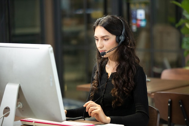 Mujer joven usando teléfono móvil mientras está sentada en la mesa