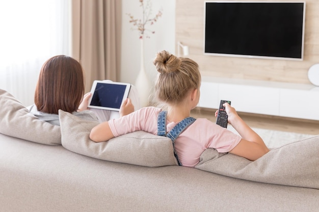 Mujer joven usando teléfono móvil mientras está sentada en el sofá en casa