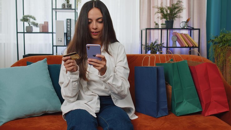 Foto mujer joven usando teléfono móvil mientras está sentada en el sofá en casa