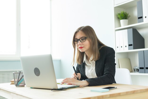 Foto mujer joven usando teléfono móvil mientras está sentada en la mesa