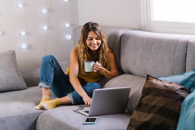 Foto mujer joven usando teléfono móvil mientras está sentada en el sofá