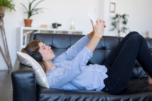 Foto mujer joven usando el teléfono en el sofá en casa