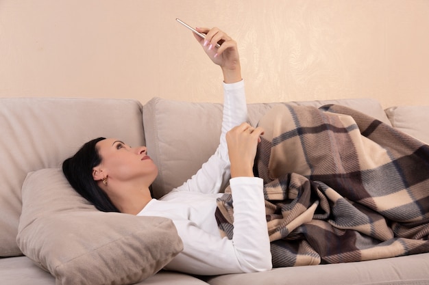 Mujer joven usando un teléfono en el sofá