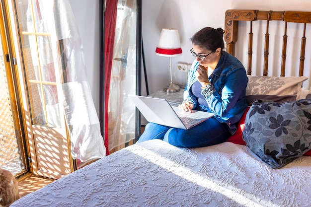 mujer joven, usar la computadora portátil, en el dormitorio