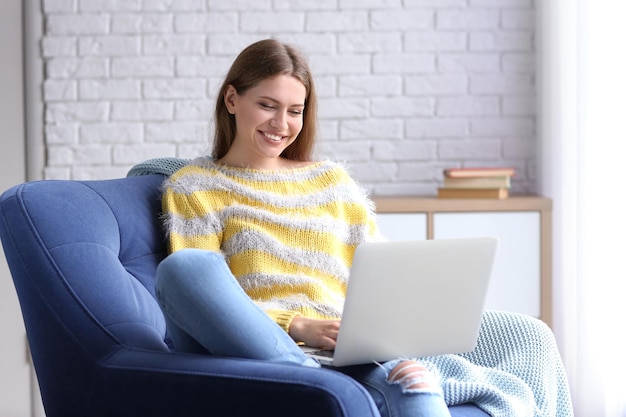 Mujer joven, usar la computadora portátil, en el interior