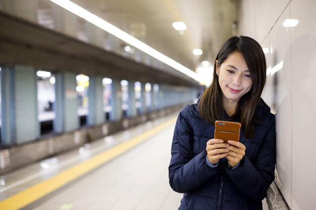Mujer joven uso de teléfono móvil en el metro de la ciudad de tokio
