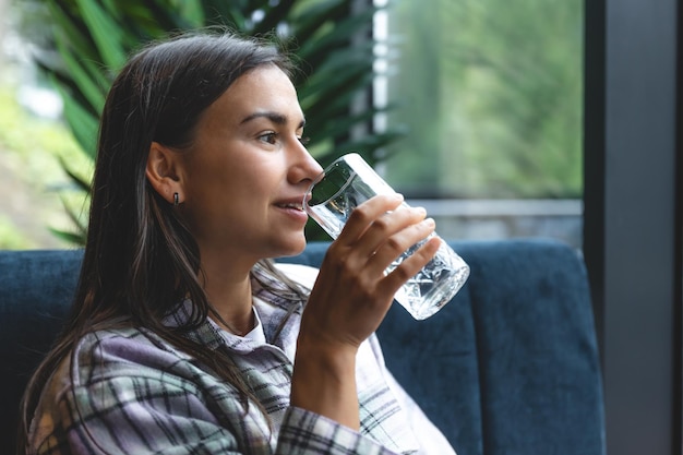 Una mujer joven con un vaso de agua en un café.