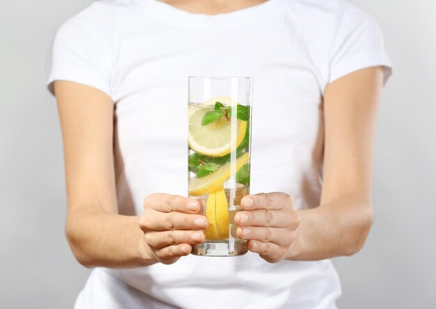 Foto mujer joven con vaso de limonada en primer plano de fondo gris