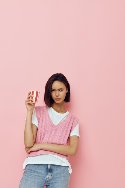 Mujer joven con un vaso en la mano camiseta rosa estilo verano Estilo de vida inalterado