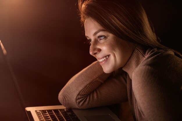 Mujer joven ve videos en internet en su computadora portátil en casa nig