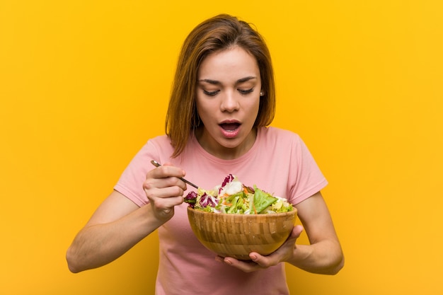 Mujer joven vegana comiendo una ensalada fresca y deliciosa.