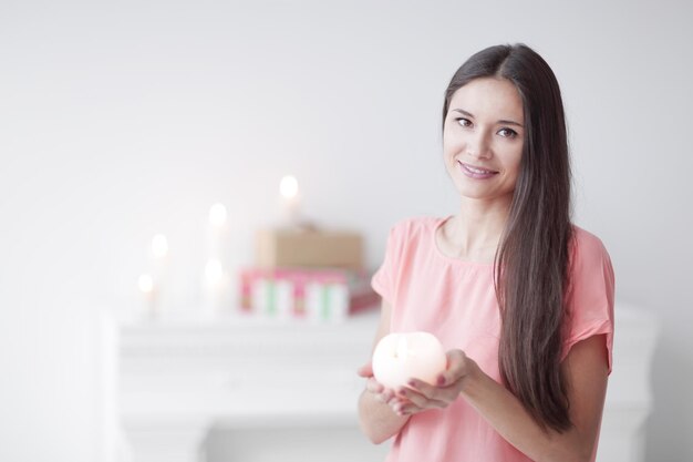 Mujer joven con una vela decorativa sobre un fondo de una sala de estar luminosa