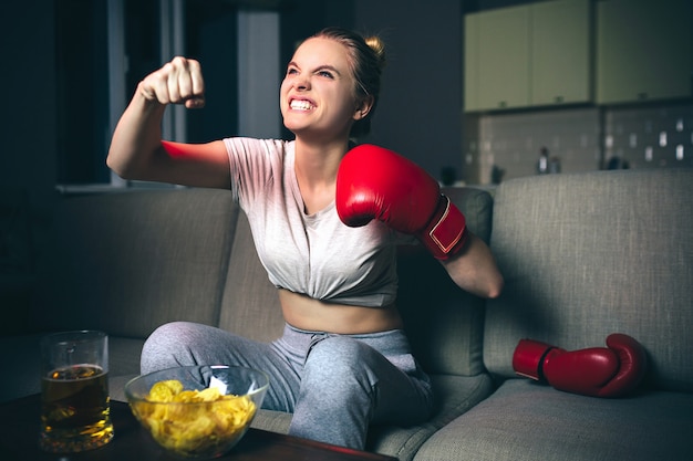 Mujer joven ver boxeo en la televisión por la noche