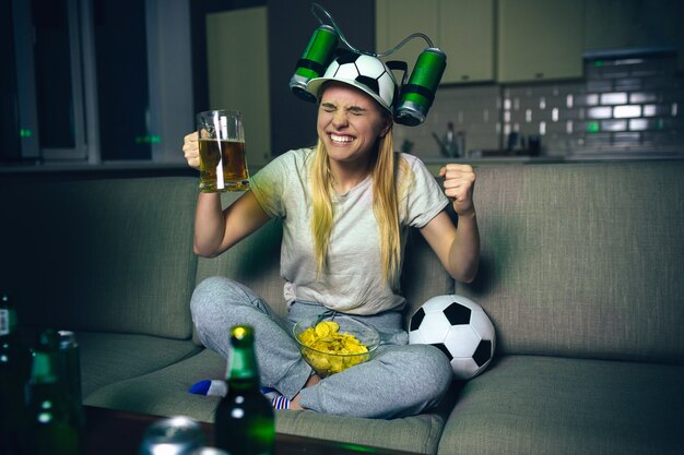 Mujer joven ver partido de fútbol en la televisión por la noche