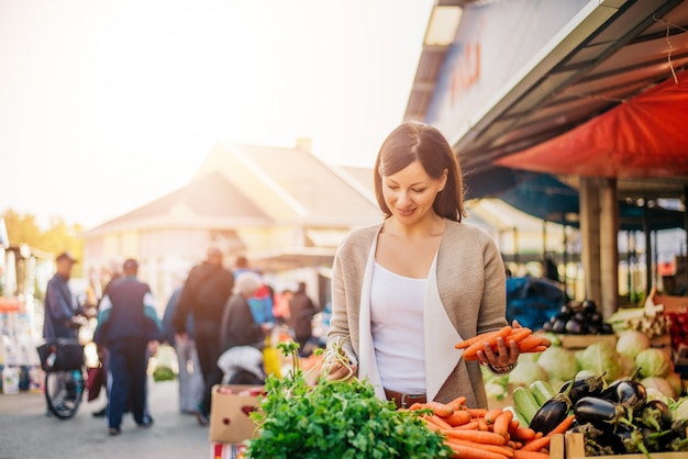 Mujer joven en las verduras de compra del mercado.