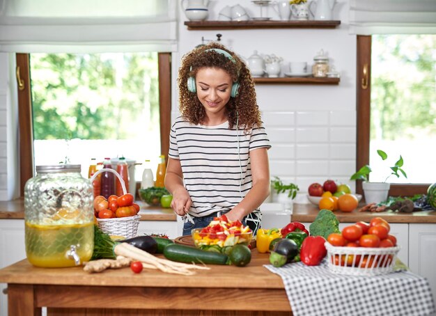 Foto mujer joven con verduras en la tabla de cortar en casa