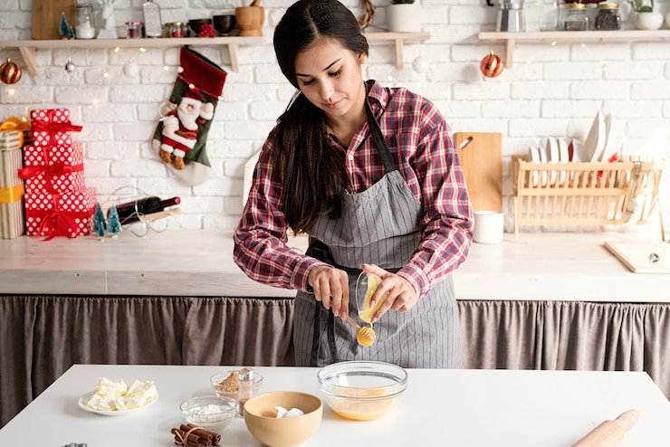 Foto mujer joven vertiendo la miel para cocinar la masa en la cocina