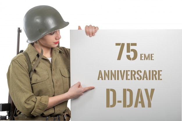 Mujer joven vestida con el uniforme militar de wwii con casco que muestra el letrero con el aniversario del día D