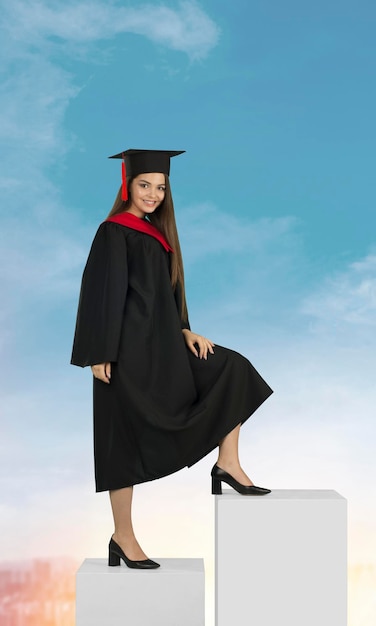 Mujer joven vestida con un vestido de graduación sube la escalera de la carrera en el fondo del cielo azul