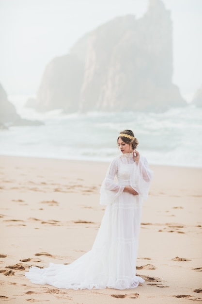 mujer joven en vestido blanco caminando en la playa