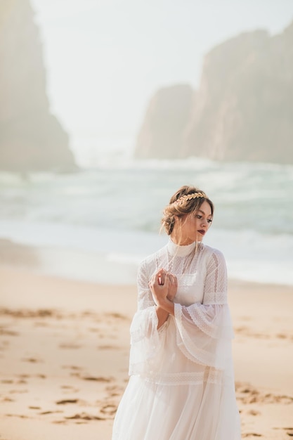 mujer joven en vestido blanco caminando en la playa