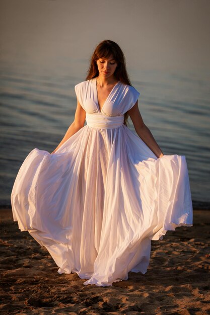 Mujer joven con vestido blanco en la playa