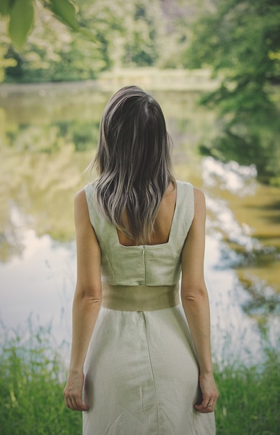 Foto mujer joven en vestido estancia junto a un lago