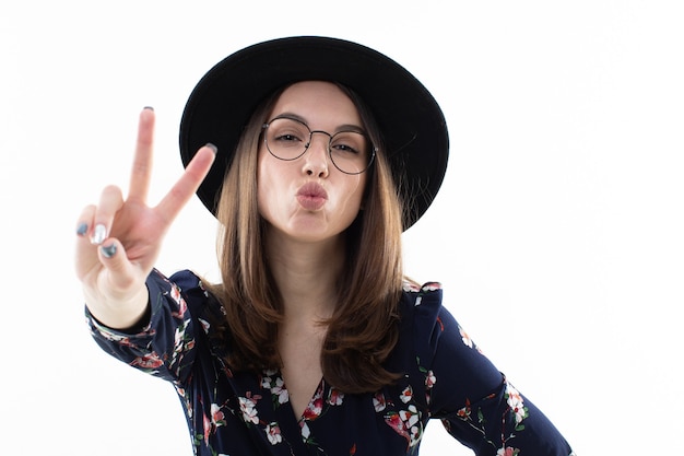 Mujer joven con un vestido largo de flores con un sombrero posa para la cámara