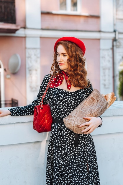 Mujer joven en vestido negro sosteniendo un paquete de papel de baguettes francesas Foto de comida de panadería de pan