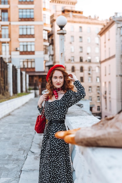 Mujer joven en vestido negro sosteniendo un paquete de papel de baguettes francesas Foto de comida de panadería de pan