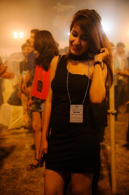 Foto mujer joven con vestido de pie al aire libre por la noche