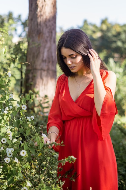 mujer joven en vestido rojo en un bosque disfrutando de la naturaleza