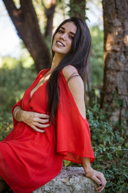 mujer joven en vestido rojo en un bosque disfrutando de la naturaleza