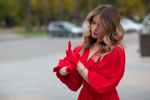 Mujer joven en vestido rojo se pone guantes médicos