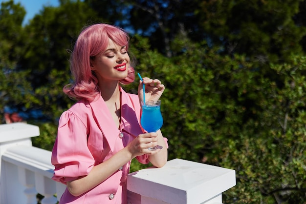 Mujer joven en vestido rosa al aire libre con cóctel concepto de relajación foto de alta calidad