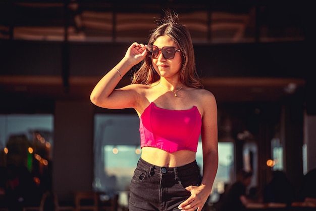 Mujer joven con vestido rosa y ropa informal posando en un centro comercial